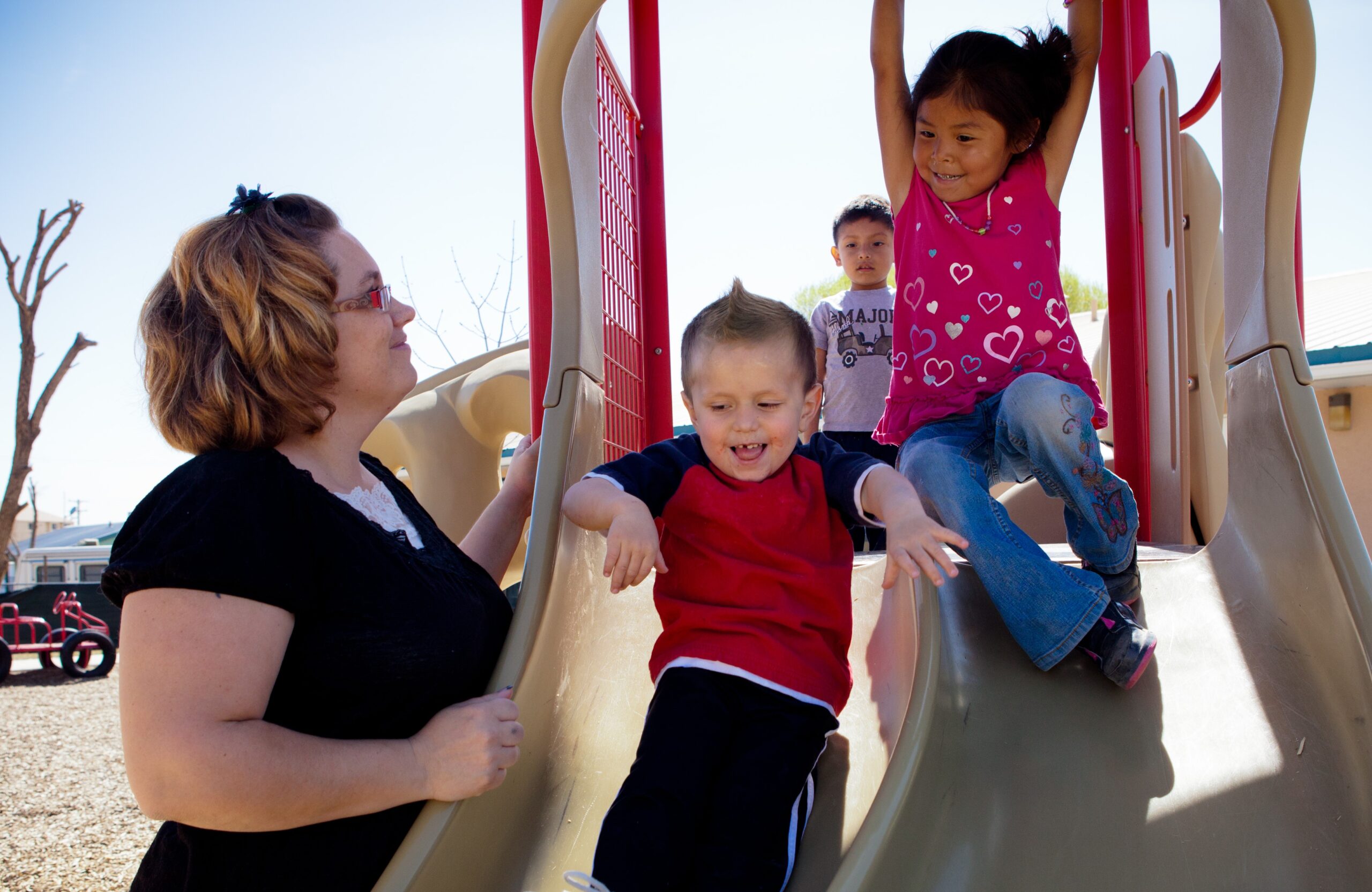 Caregiver watching her children play on the slide at the playground